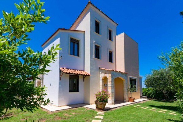 A two-story house with a tiled roof, a small garden, and a clear blue sky. - Villa Kefalas Large Private Pool, A/C, WiFi (Apokoronos)