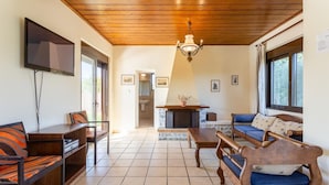 A living room with a fireplace, wooden furniture, and a TV mounted on the wall. - Villa Kefalas Large Private Pool, A/C, WiFi (Apokoronos)