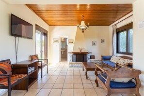 A living room with a fireplace, wooden furniture, and a TV mounted on the wall. - Villa Kefalas Large Private Pool, A/C, WiFi (Apokoronos)
