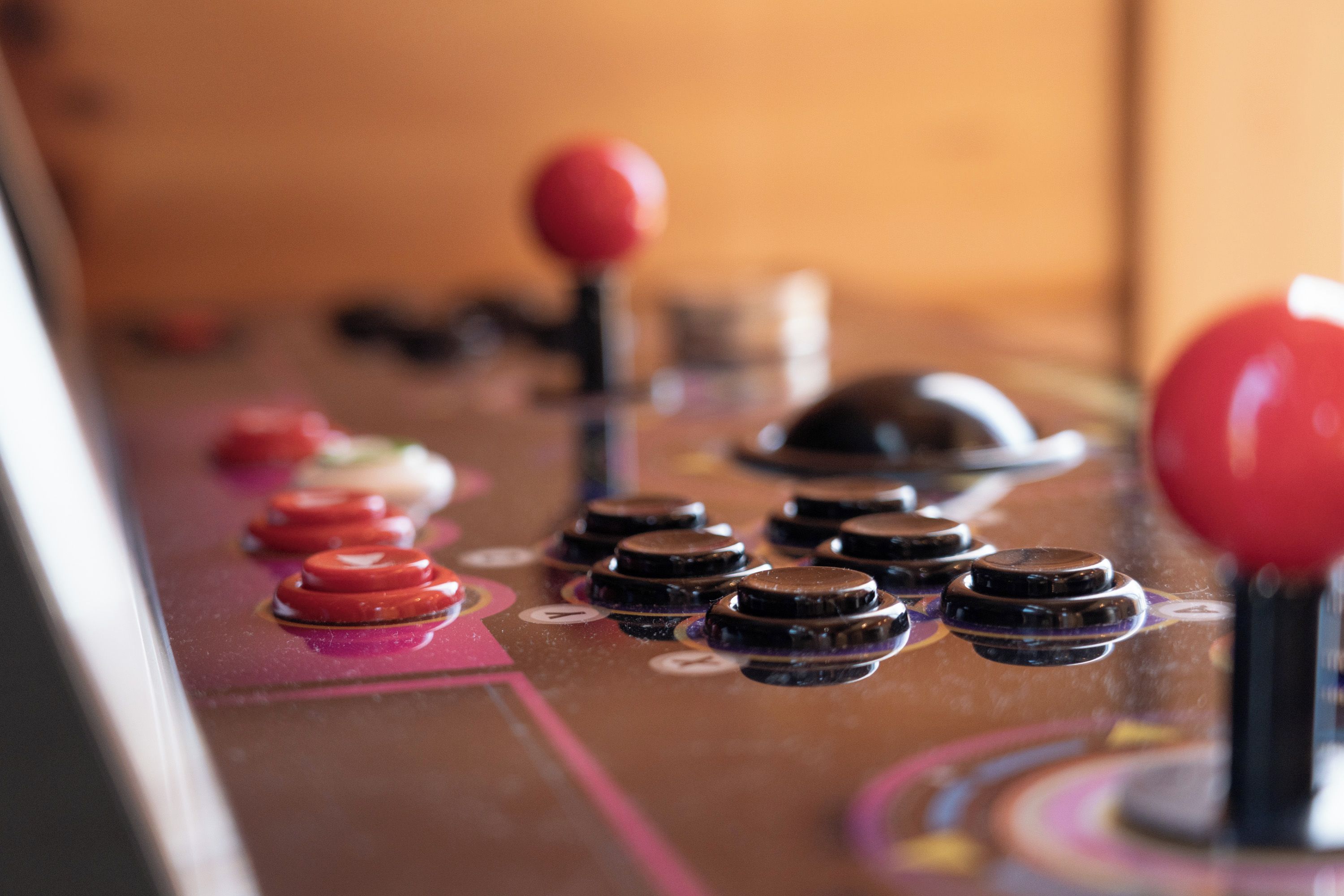 A close-up of a joystick control panel with red and black buttons.