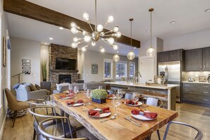 Enjoy meals in this well-appointed dining area with a long table, modern kitchen, and cozy seating area.