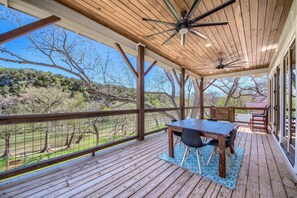 A wooden deck with a table and chairs, overlooking a grassy area with trees. - River Repose Rr 7134 4 Bedroom Home by RedAwning (New Braunfels)