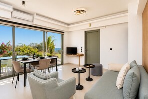 A modern living room with a dining area, a television, and a balcony with a view.