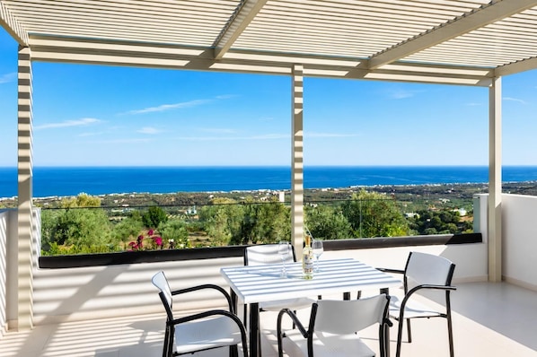 Ein Balkon mit Tisch und Stühlen mit Blick auf eine Küstenlandschaft.