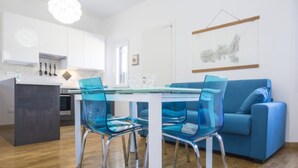 Una cucina moderna con mobili bianchi, un tavolo da pranzo in vetro e sedie blu.