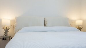 Un letto rifatto con due cuscini e due abat-jour con basi decorate.