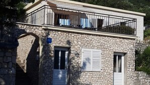 A stone building with a balcony, two doors, and a sign indicating it is a guesthouse. - House DANIVA located in front of the sea (Okuklje)
