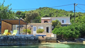A coastal property with a stone building, a pool, and yellow lounge chairs. - House DANIVA located in front of the sea (Okuklje)
