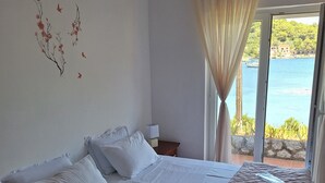 A hotel room with two beds, a view of the sea, and a window with curtains. - House DANIVA located in front of the sea (Okuklje)