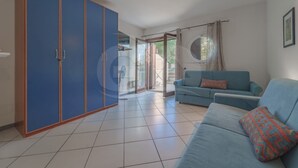 A spacious living room with a blue sofa, a patterned throw pillow, and a large wardrobe. - Studio 4 with sea view pool in a panoramic position above the village of Porto Azzurro (Porto Azzurro)