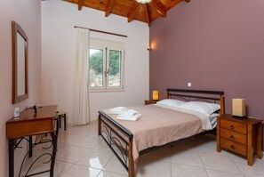 A bedroom with a bed, bedside tables, a desk, and a window with curtains.