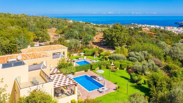 Una propiedad residencial con piscina, un patio con mobiliario exterior y vistas al mar.