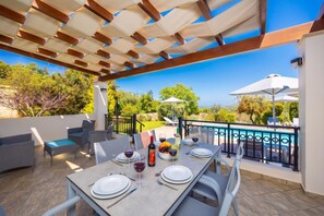 An outdoor dining area with a table set for two, a pool, and a view of the landscape.