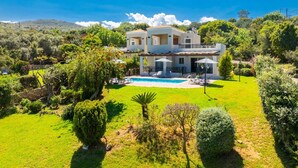 A two-story house with a swimming pool, surrounded by lush greenery and hills in the background. - Villa Georgia - Three Bedroom Villa, Sleeps 6 (Crete)