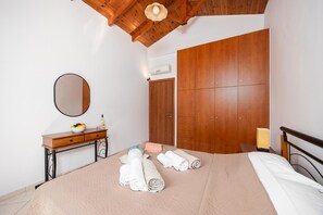 Ein Schlafzimmer mit einem Bett, einem Holzschrank, einem Nachttisch mit Spiegel und einer Lampe.