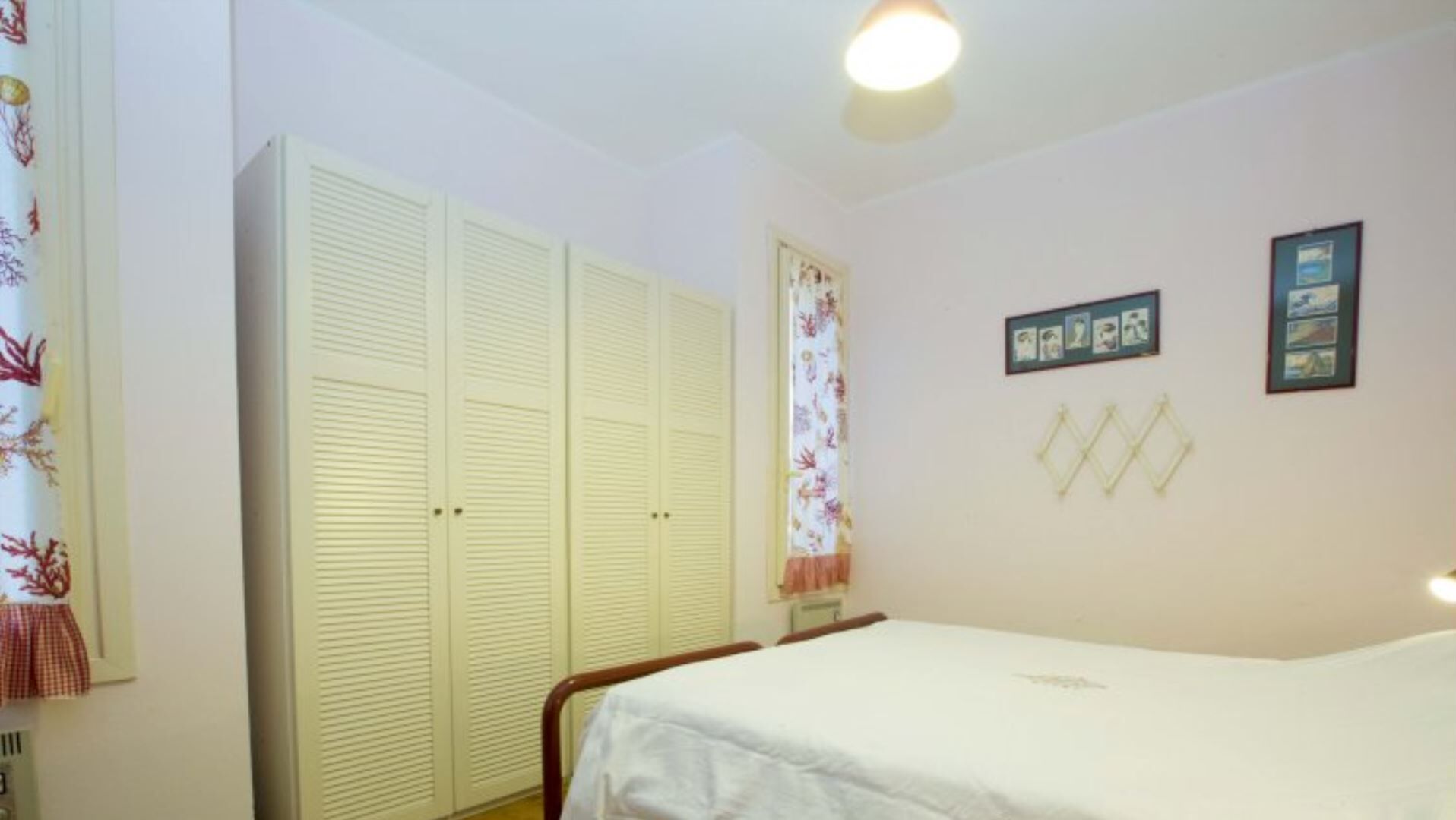 Ein Schlafzimmer mit Bett, Schrank und einem Fenster mit Vorhängen.