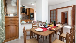 Un comedor con una mesa de madera dispuesta para una comida, rodeada de sillas de madera.