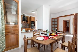 Un comedor con una mesa de madera dispuesta para una comida, rodeada de sillas de madera.