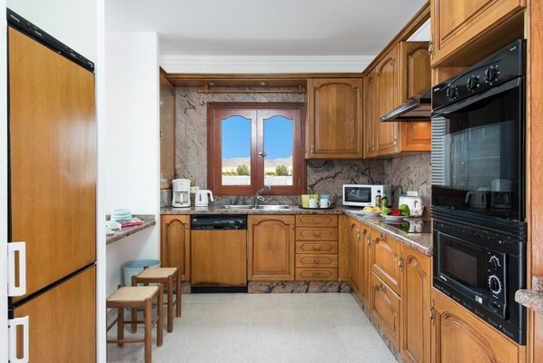 Una cocina compacta con armarios de madera, horno integrado, microondas y cafetera.