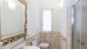 A bathroom with a large ornate mirror, a toilet, and a shower area.