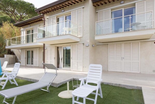 A two-story building with a balcony and a covered outdoor seating area with white lounge chairs. - RIO MARINA CHARME E RELAX (Rio Marina)