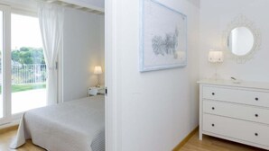 A bedroom with a bed, a nightstand, a dresser, a mirror, and a framed picture on the wall.