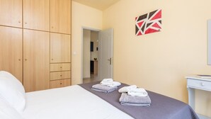 Et hotelværelse med en seng, et skab, et skrivebord og et badeværelse, der kan ses gennem en åben dør.