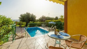 Un área de piscina en la azotea con barandilla de vidrio, una mesa con sillas y vista al mar.