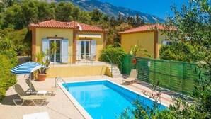 Zona de piscina con dos edificios pequeños, una piscina y vistas a la montaña.