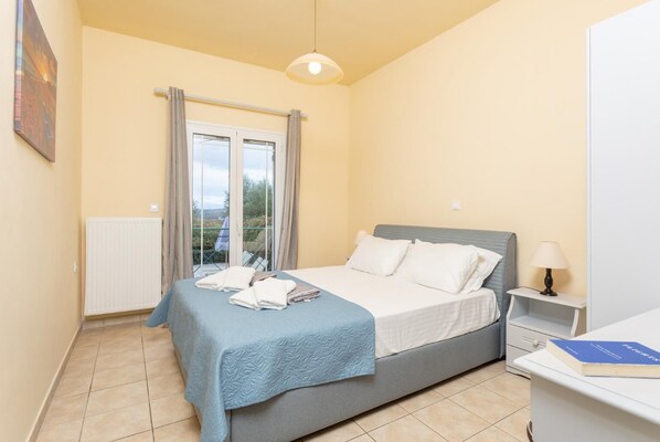 Une chambre à coucher avec un lit, une table de chevet avec une lampe, une fenêtre avec des rideaux et un radiateur.