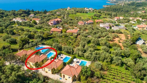 Vista aérea de una zona residencial costera con casas, una extensa masa de agua y un área de piscina destacada.