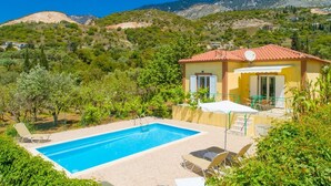 En villa med swimmingpool, omgivet af frodigt grønt og bjerge.