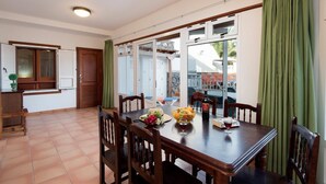 A dining area with a table set for two, a window with curtains, and a view of an outdoor area. - Villa Ramos Uno - Four Bedroom Villa, Sleeps 8 (Puerto Calero)