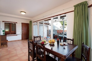 Un comedor con una mesa dispuesta para dos, una ventana con cortinas y vistas a un espacio exterior.