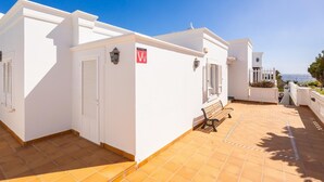 A white building with a 'V' sign, a bench, and a view of the sea. - Villa Ramos Uno - Four Bedroom Villa, Sleeps 8 (Puerto Calero)