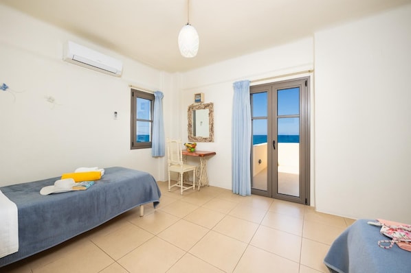 Ein Zimmer mit Bett, Schreibtisch, Stuhl, Spiegel und Meerblick durch eine Schiebetür.