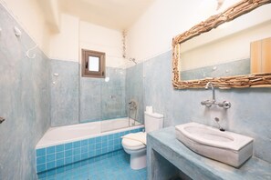 Un baño con bañera, inodoro y lavabo, todo con azulejos azules.