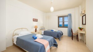 Ett hotellrum med två sängar, ett skrivbord, en stol, ett fönster med utsikt och ett litet bord med en fruktskål.