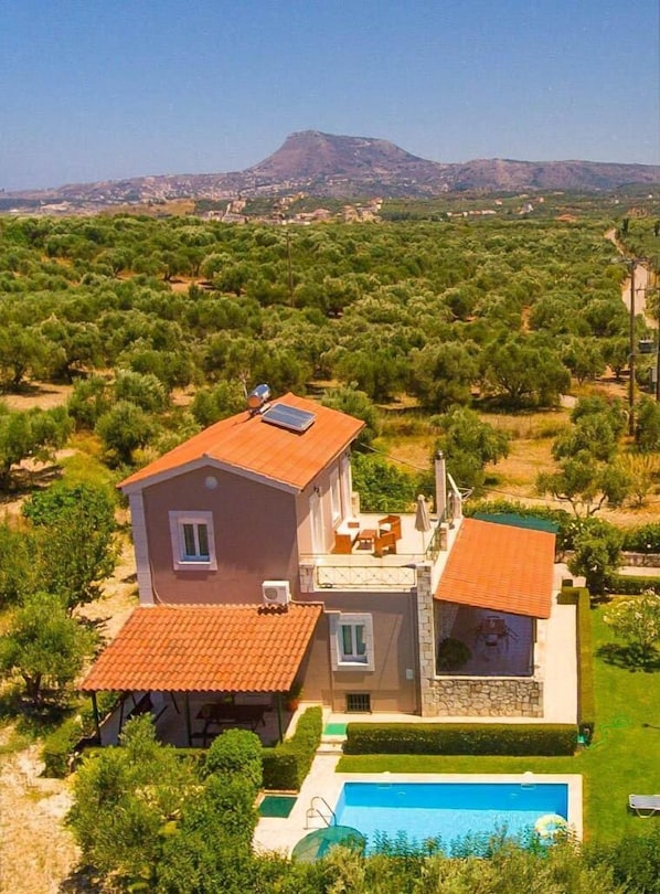 A two-story house with a swimming pool, surrounded by olive groves and a mountain in the background. - Villa Giannis - Three Bedroom Villa, Sleeps 6 (Apokoronos)