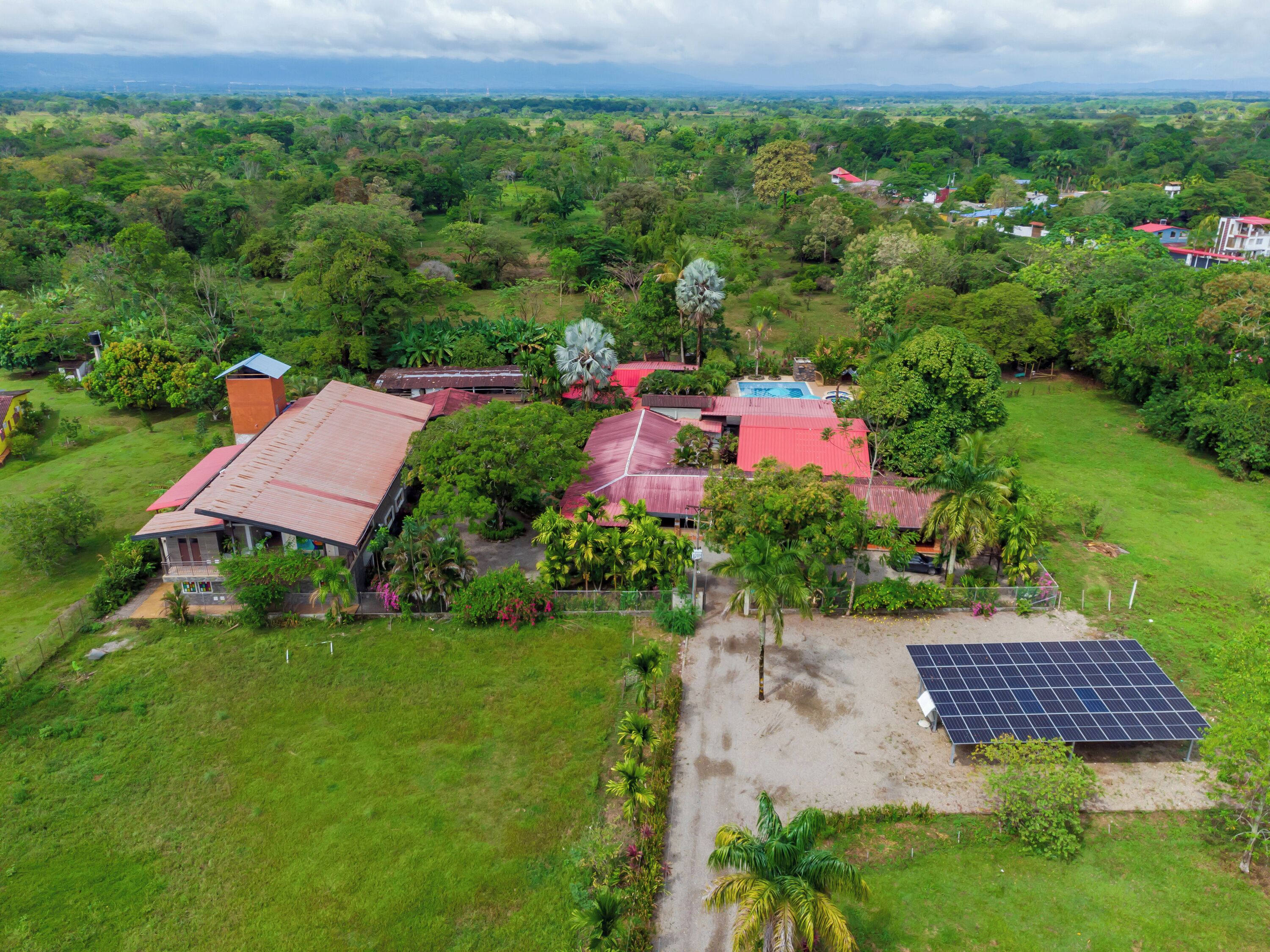 An aerial view of a residential area with houses, a swimming pool, and solar panels.