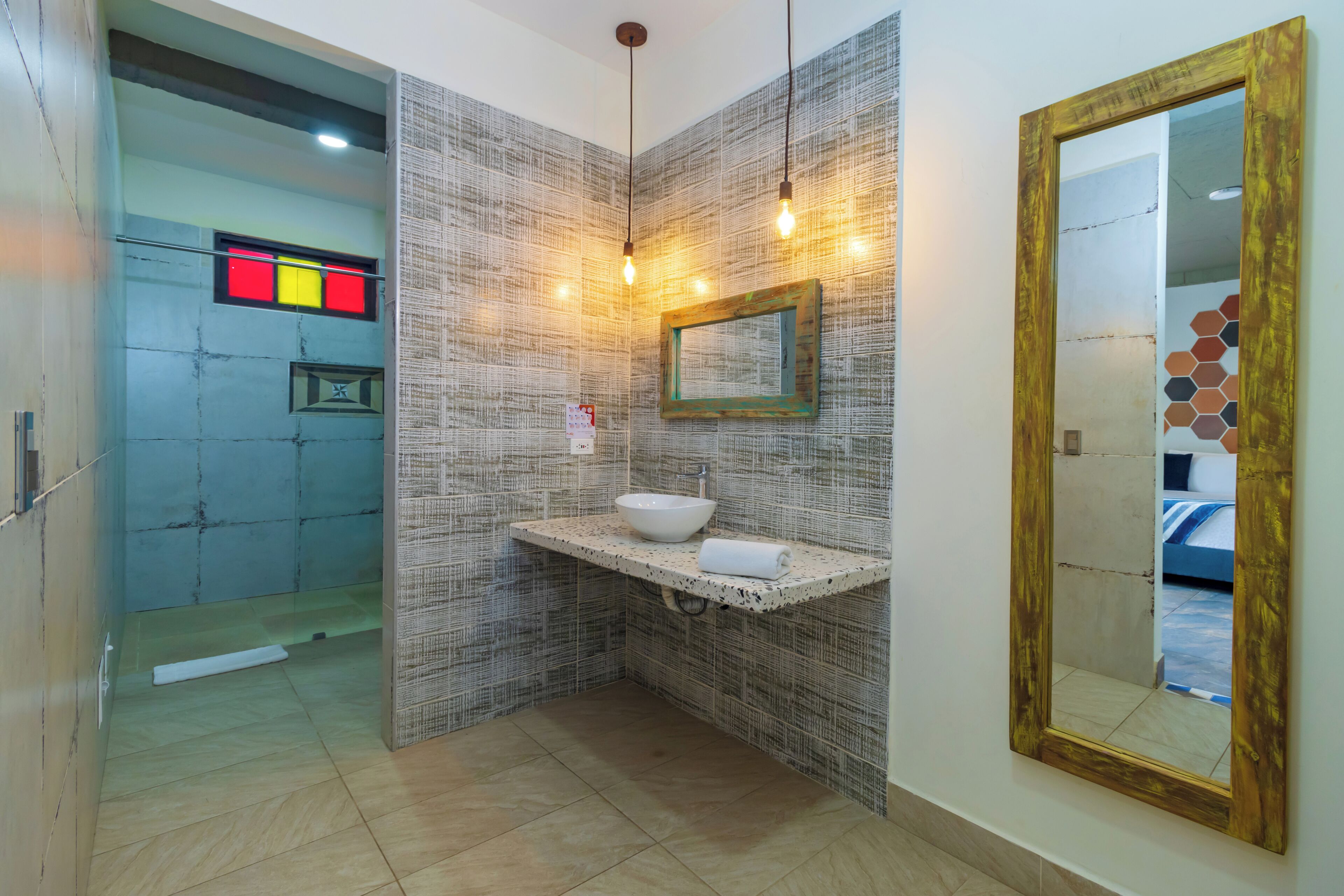 A bathroom with a modern design, featuring a large mirror, a sink with a bowl, and a shower area.