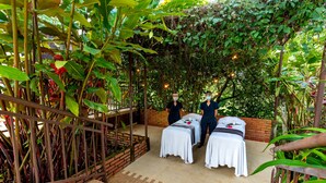 A spa area with two massage tables, surrounded by lush greenery and bamboo. - NQ Hotel Orinoquía (Villavicencio)