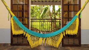A hammock set up between two glass doors with a view of a garden. - NQ Hotel Orinoquía (Villavicencio)