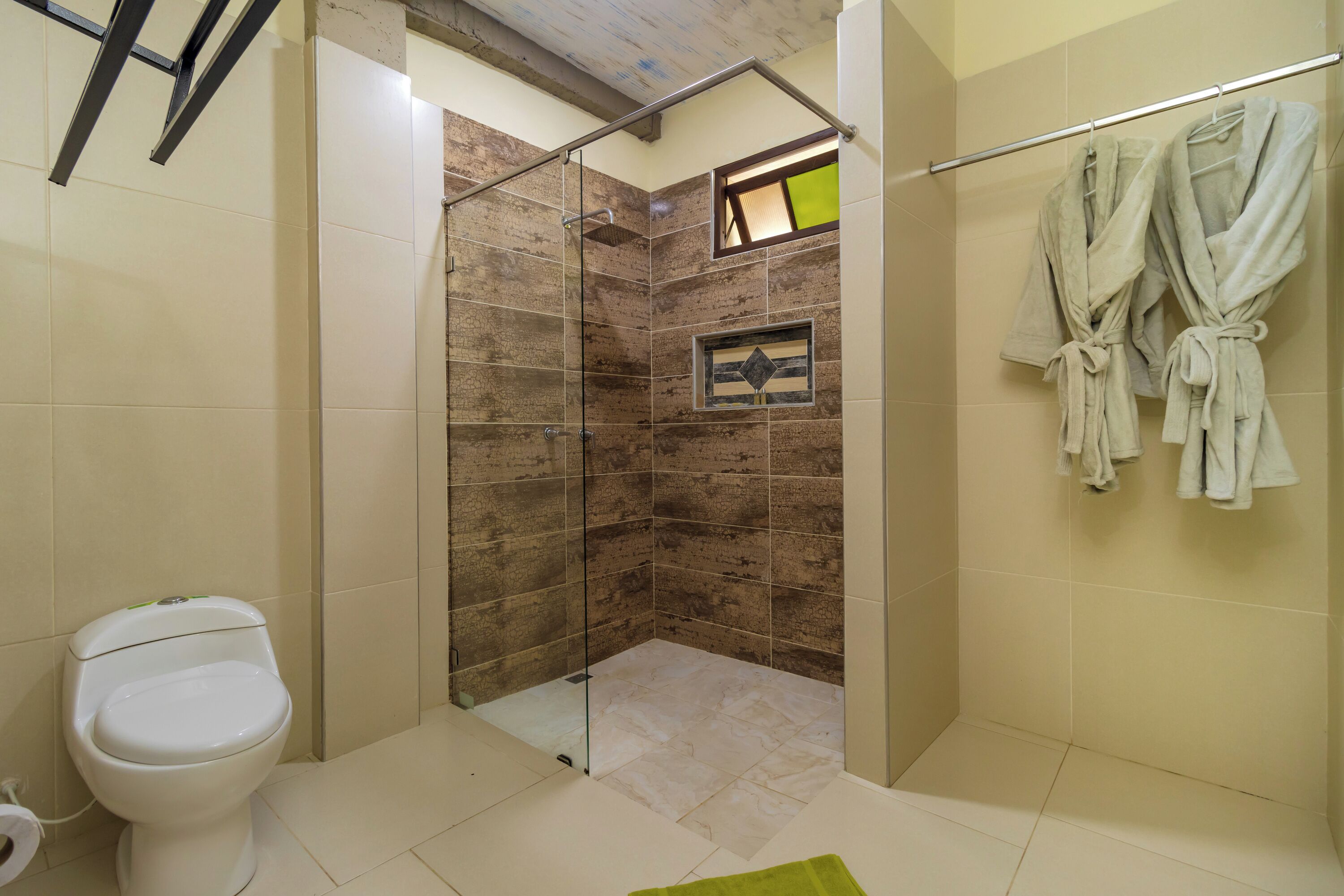 Une salle de bain avec une douche, des toilettes et un porte-serviettes avec des peignoirs.