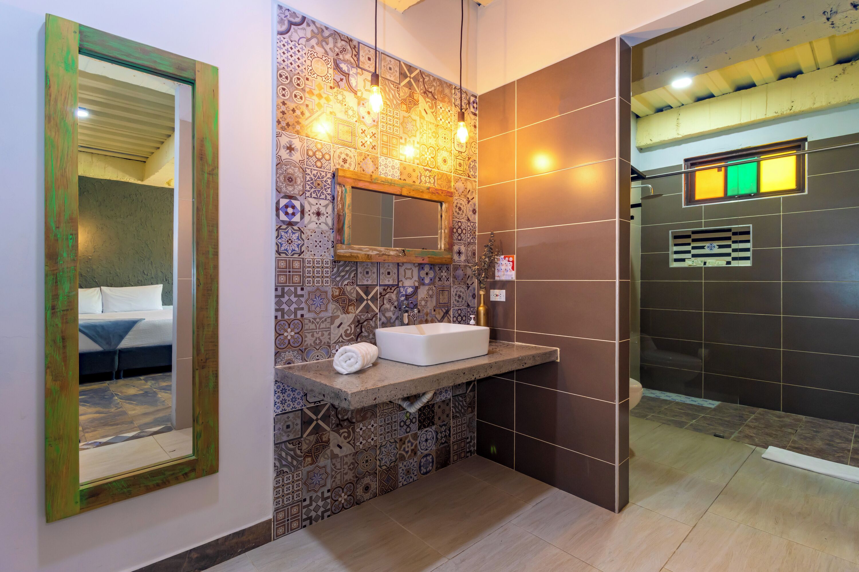 Une salle de bain avec un mur carrelé, un lavabo, un miroir et un espace douche.
