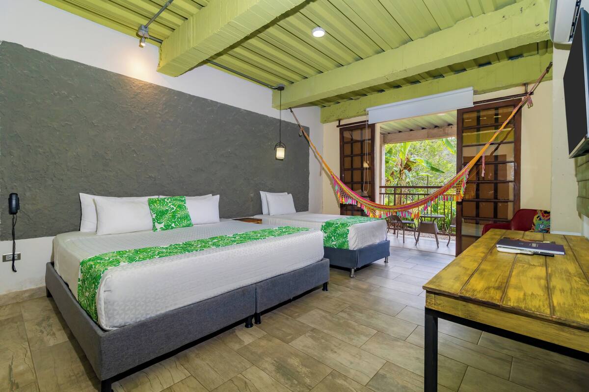 A bedroom with two beds, a wooden table, and a hammock.