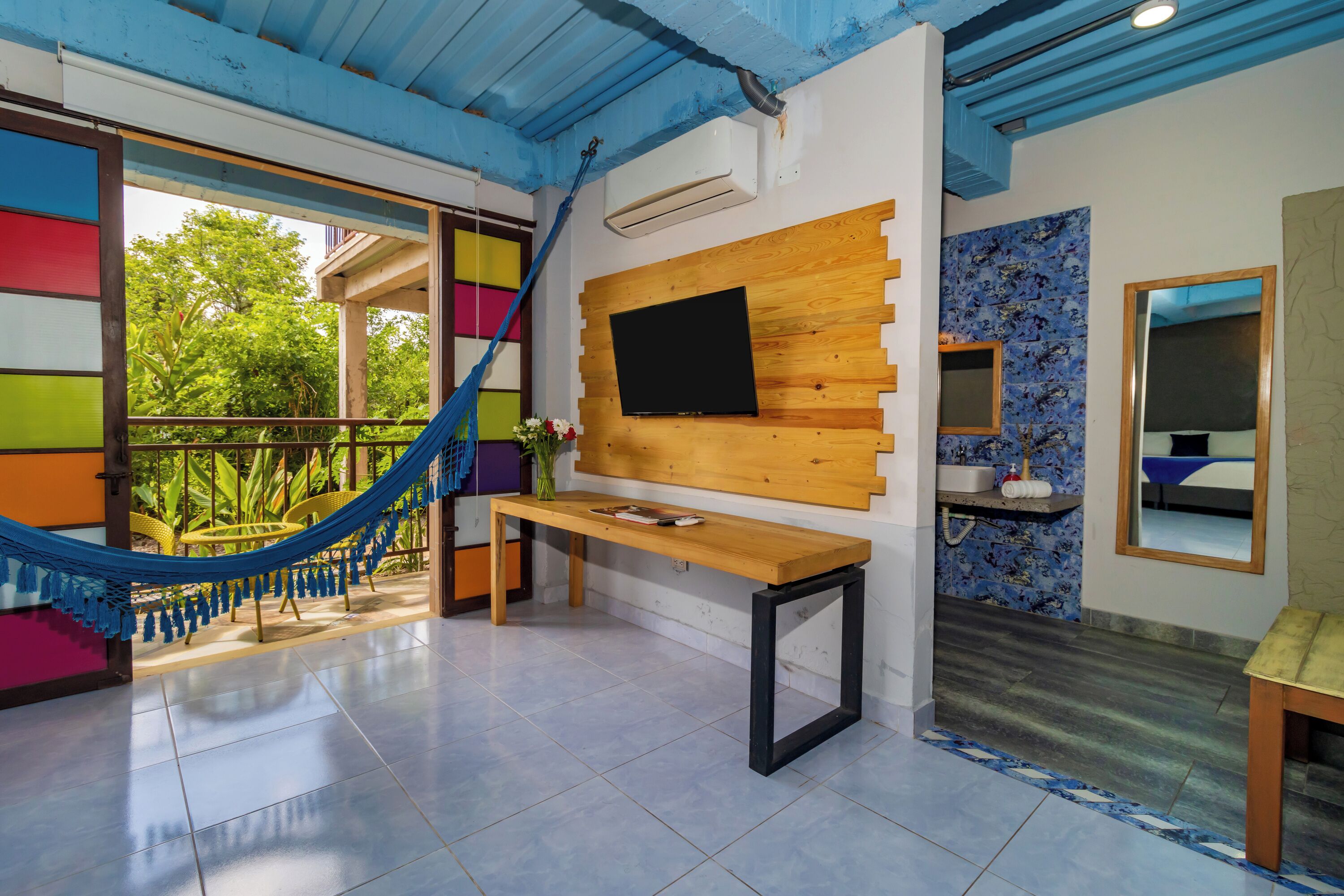 A modern living room with a hammock, a wooden TV stand, and a tiled floor.