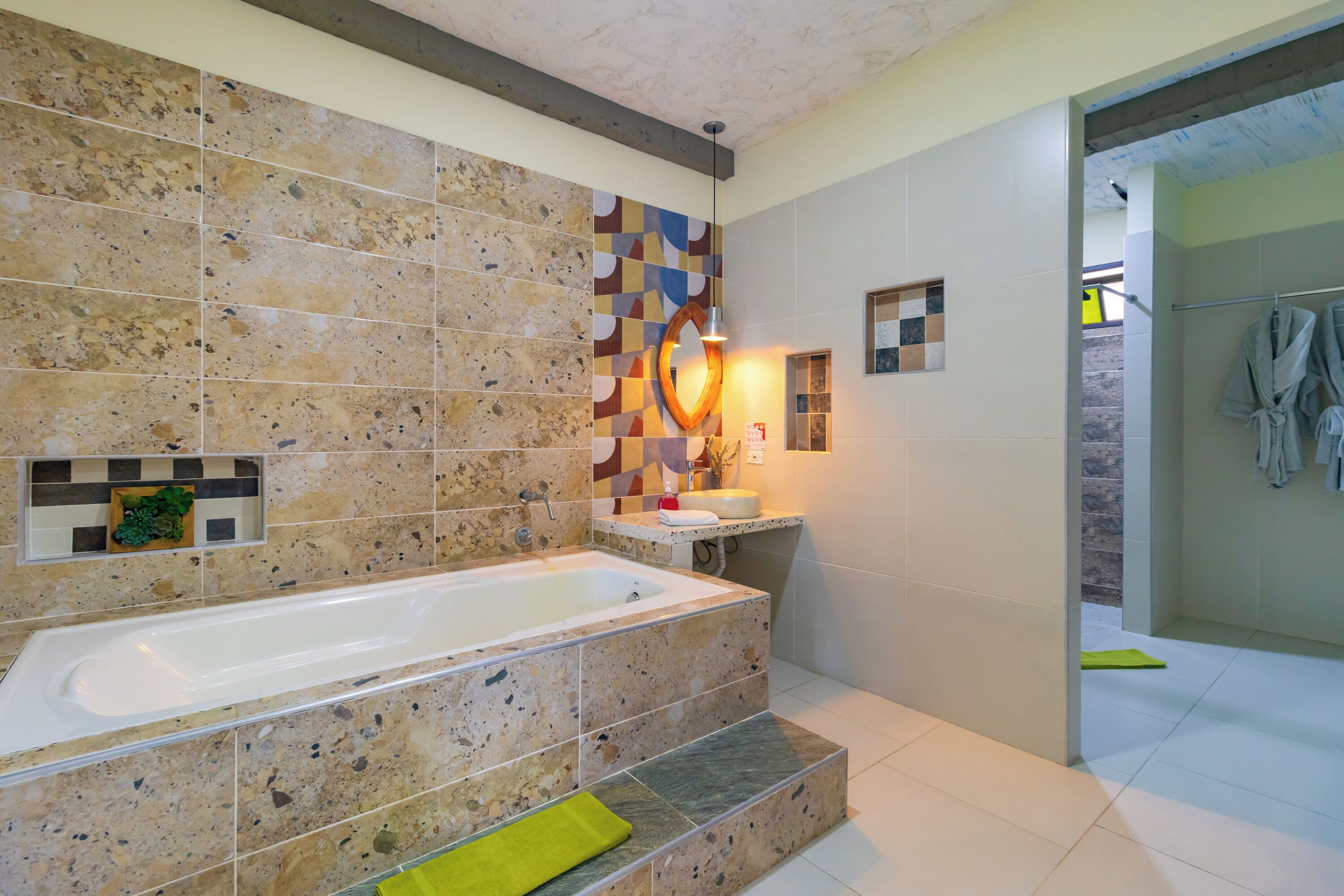 Un baño moderno con una bañera independiente, una zona de ducha y una pared de azulejos con diseño geométrico.