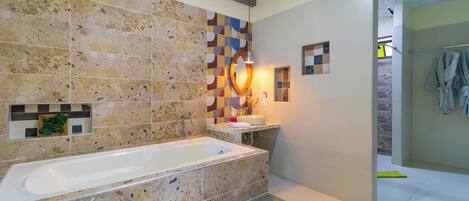 Un baño moderno con una bañera independiente, una zona de ducha y una pared de azulejos con diseño geométrico.