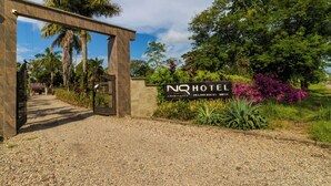 A hotel entrance with a gravel path leading to a wooden archway. - NQ Hotel Orinoquía (Villavicencio)